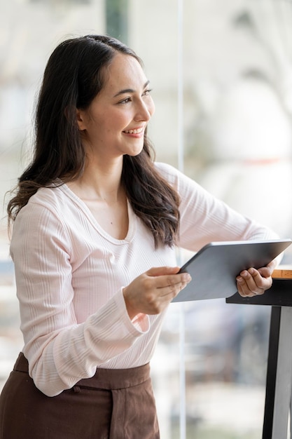 Belle femme d'affaires debout au bureau avec tablette numérique