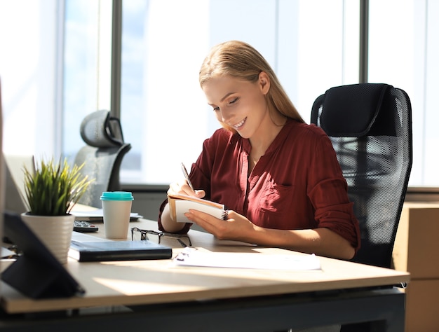 Belle femme d'affaires écrit quelque chose alors qu'elle était assise dans le bureau.