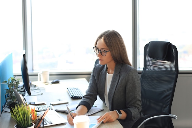 Belle femme d'affaires écrit quelque chose alors qu'elle était assise dans le bureau.