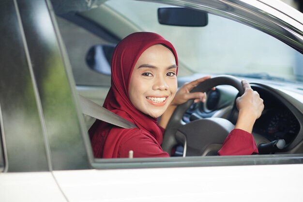 Belle femme d'affaires avec hijab sourit dans sa voiture