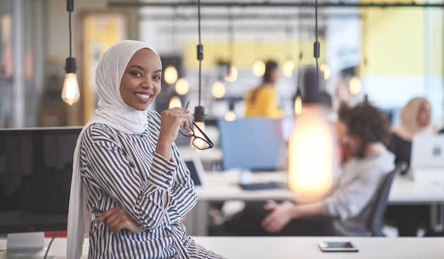 belle femme d'affaires musulmane africaine moderne au bureau, portant le hijab dans un espace de coworking de démarrage moderne et créatif