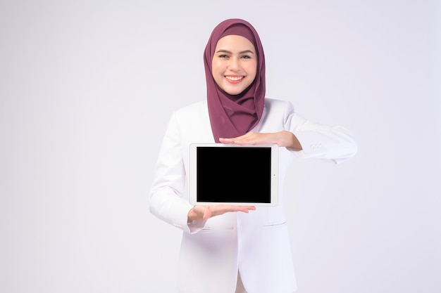 Belle femme d'affaires musulmane portant un costume blanc avec hijab tenant une tablette en studiox9