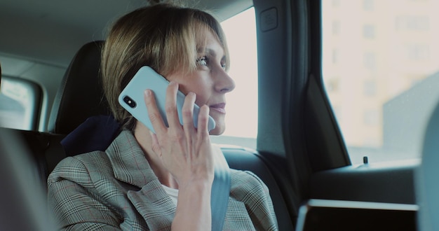 Belle femme d'affaires parlant au téléphone en voiture travaillant sur un ordinateur portable à l'aide de technologies dans le concept de voiture