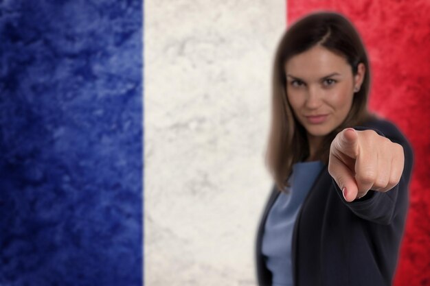 Belle femme d'affaires pointant son doigt sur votre fond de drapeau français.