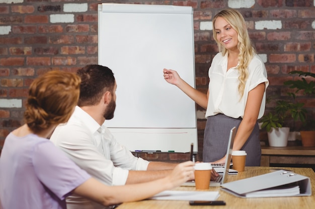 Belle femme d&#39;affaires pointant vers le tableau blanc