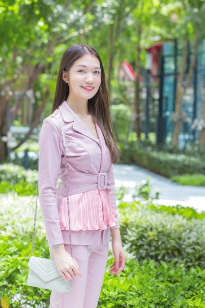 Belle femme d'affaires professionnelle asiatique aux cheveux longs portant une chemise rose sourit en plein air