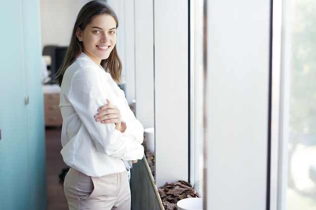 Belle femme d'affaires regarde la caméra et sourit tout en travaillant au bureau.