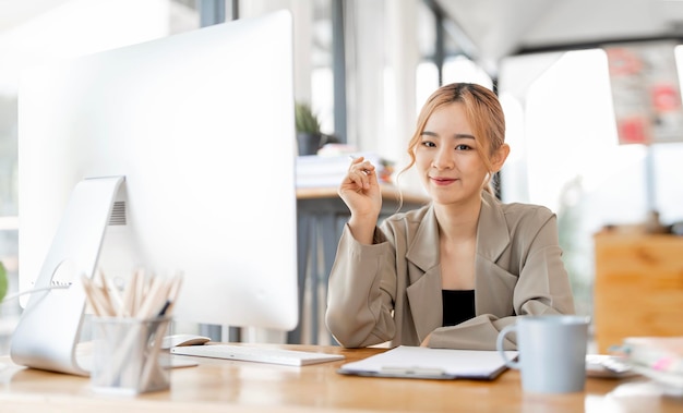 Belle femme d'affaires regarde la caméra et sourit en travaillant au bureau