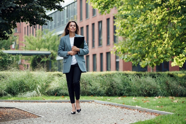 Belle femme d'affaires réussie en costume avec document marchant jusqu'à la réunion près du bureau moderne