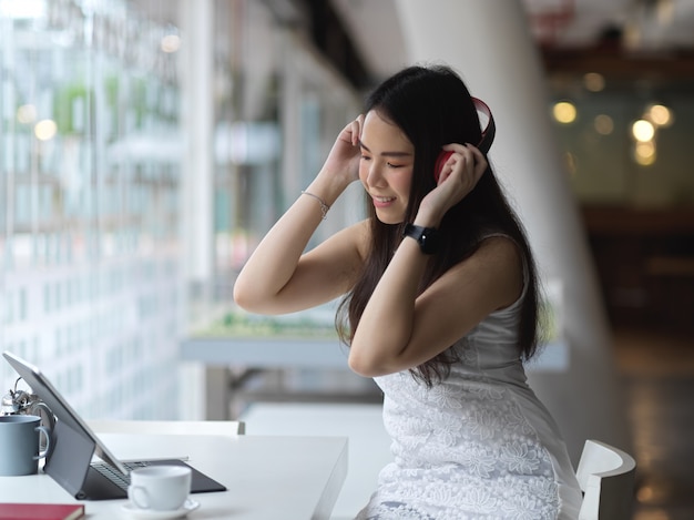 Belle femme d'affaires se détendre du travail en écoutant la musique avec des écouteurs