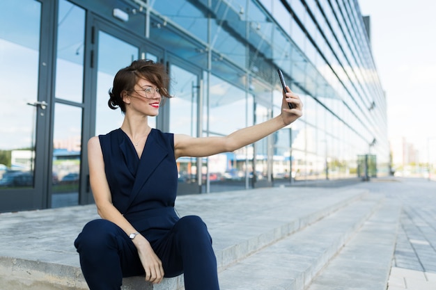 Belle femme d'affaires avec smartphone, portrait d'un manager à succès sur le fond d'un gratte-ciel