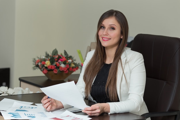 Photo belle femme d'affaires souriante travaillant à son bureau avec des documents.