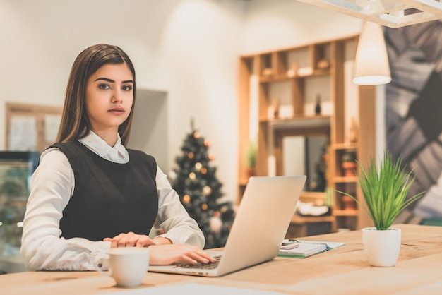 La belle femme d'affaires travaillant avec un ordinateur portable