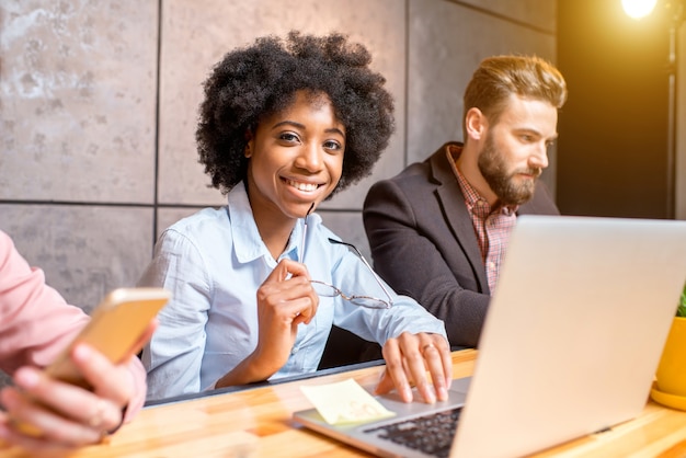 Belle femme africaine avec un bel homme caucasien travaillant avec un ordinateur portable à l'intérieur du bureau moderne