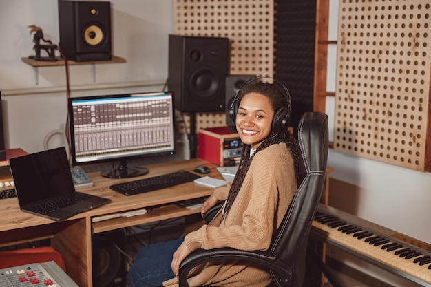 Belle femme africaine élégante ingénieur du son musicien et producteur travaillant dans une salle insonorisée de studio d'enregistrement de musique