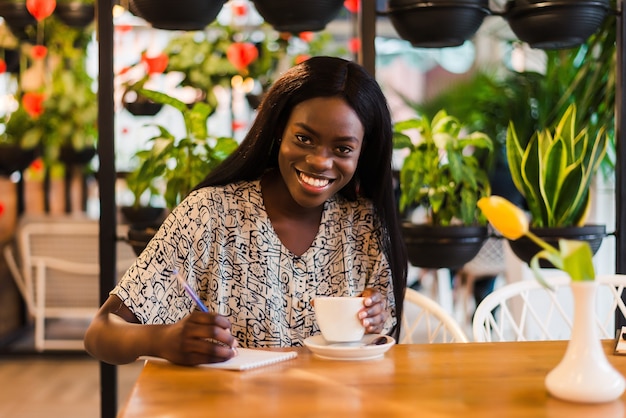 Belle femme africaine prend des notes à la cafétéria