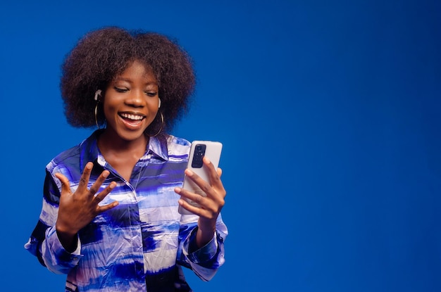 Belle femme africaine se sentant excitée par ce qu'elle a vu sur son téléphone