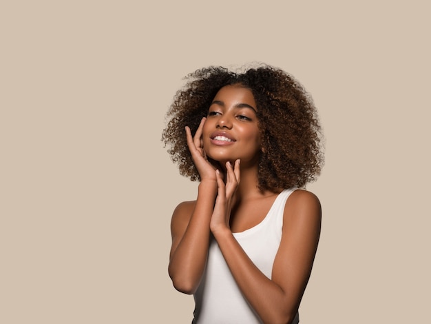 Belle femme africaine t-shirt blanc portrait coupe de cheveux afro touchant son visage Fond de couleur marron