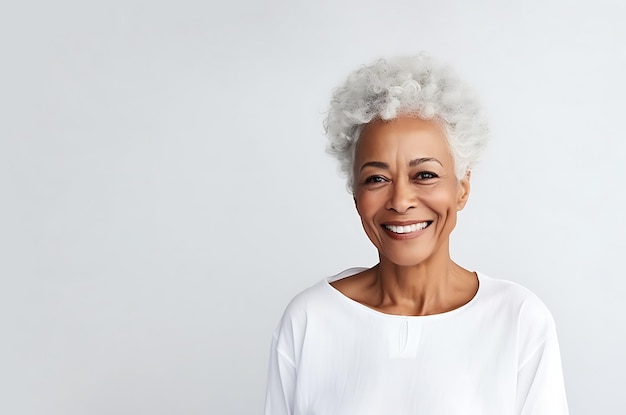 Une belle femme afro-américaine âgée en vêtements légers posant sur un fond blanc