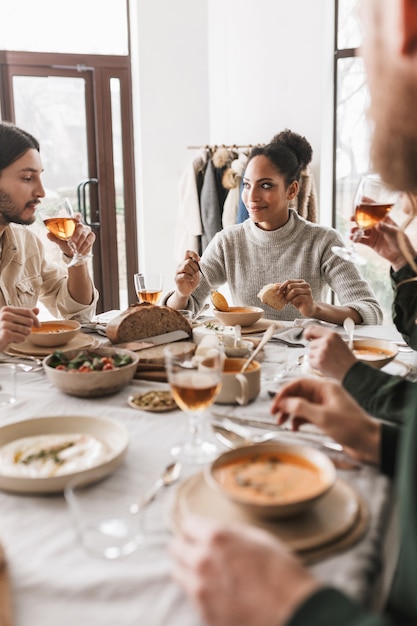 Belle Femme Afro-américaine Aux Cheveux Bouclés Sombres Assis à La Table De Manger De La Soupe Avec Une Tranche De Pain Rêveusement