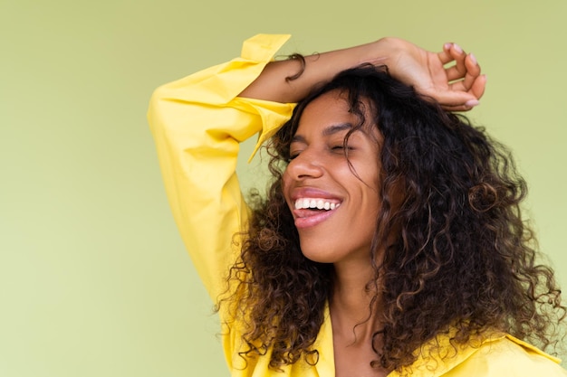 Belle femme afro-américaine en chemise décontractée sur fond vert sourire positif rire appréciant excité