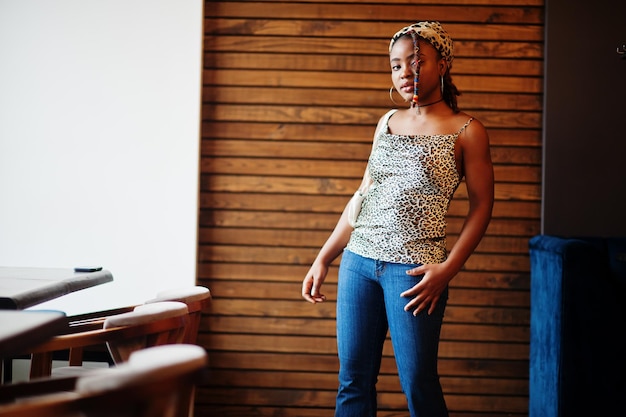 Belle femme afro-américaine avec des dreadlocks en tenue léopard au café Belle jeune fille noire à la mode cool à l'intérieur