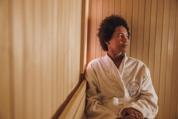 Photo belle femme afro-américaine mature profitant d'un sauna au centre de spa.