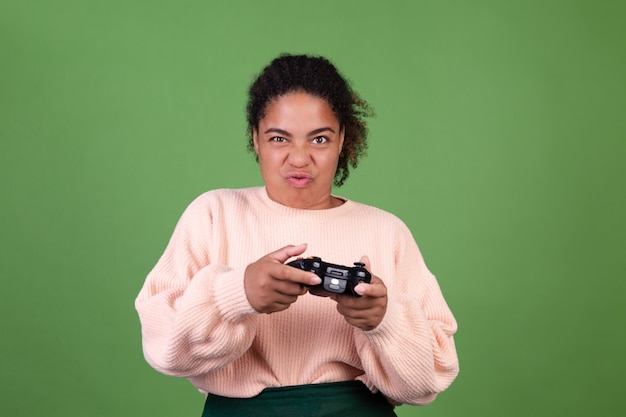 Belle femme afro-américaine sur mur vert axée sur les jeux vidéo