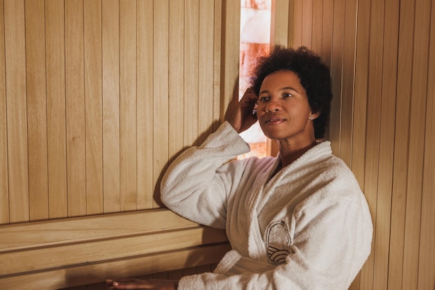 Belle femme afro-américaine mûre se relaxant dans un sauna au centre de spa.