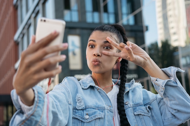 Belle femme afro-américaine prenant selfie, montrant le signe de la victoire