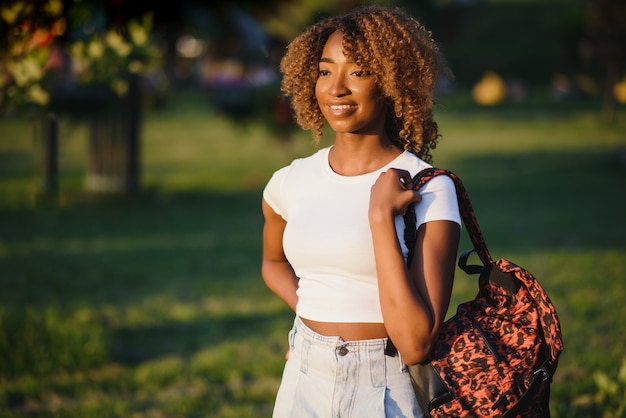 belle femme afro-américaine souriante et en détournant les yeux au parc.