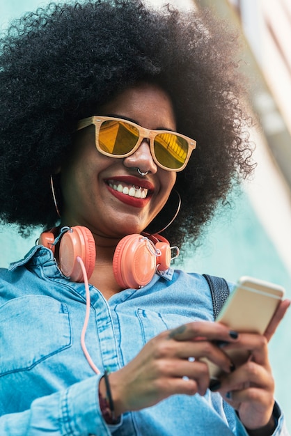 Belle femme afro-américaine utilisant un mobile dans la rue. Notion de communication.