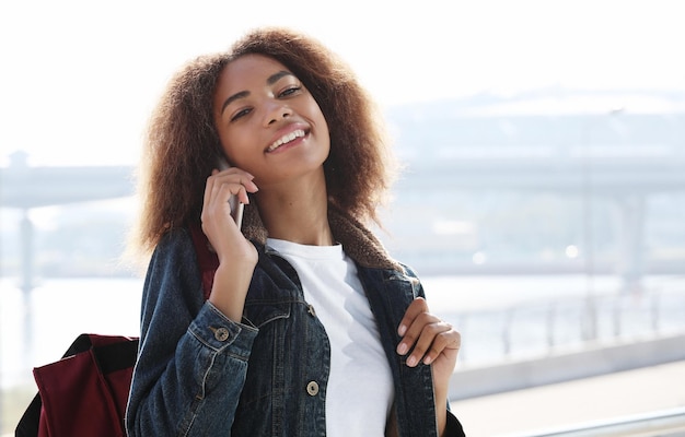 Belle femme afro-américaine utilisant un téléphone portable dans la rue