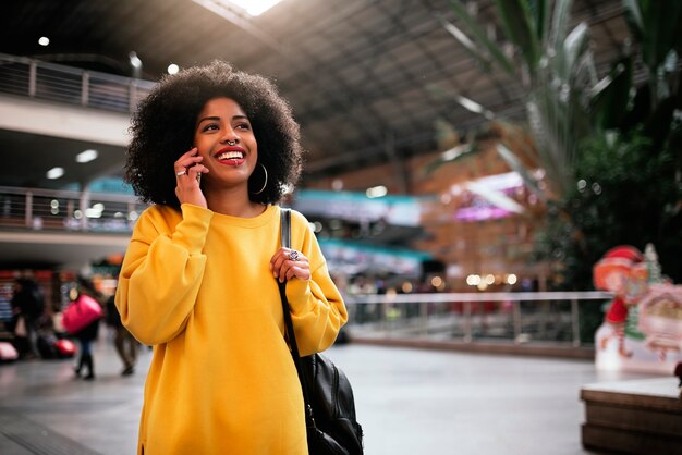 Belle femme afro utilisant le mobile dans la gare. Notion de communication.