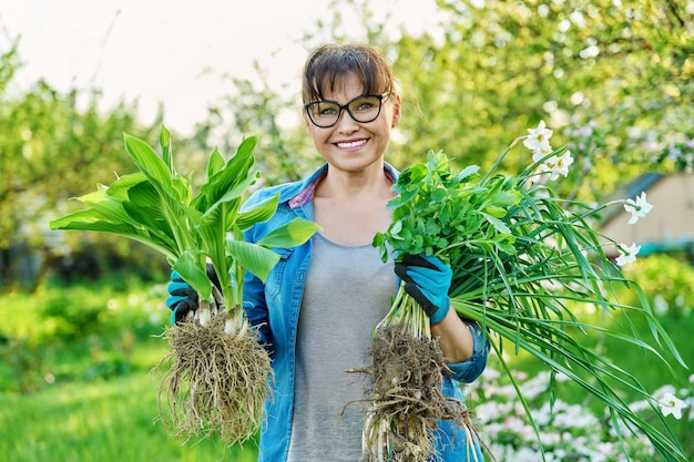 Belle femme d'âge moyen avec des plantes enracinées en regardant la caméra