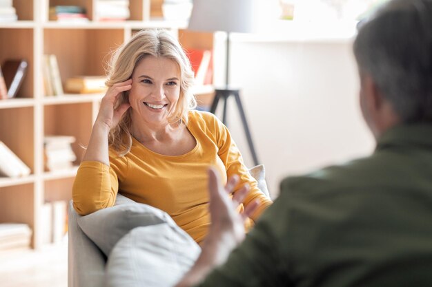 Photo belle femme d'âge moyen se détendre sur un canapé et discuter avec son mari