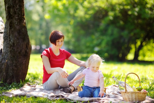 Belle femme d&#39;âge moyen et son adorable petit-fils ayant un pique-nique dans un parc ensoleillé