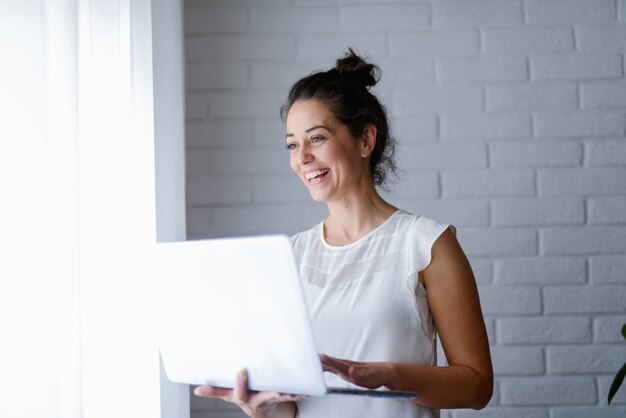 Belle femme d'âge moyen tenant la tablette dans ses mains et souriant.