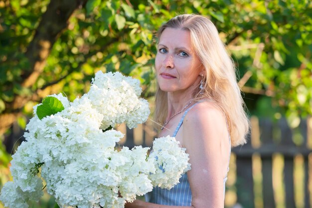 Belle femme âgée avec un bouquet de fleurs Femme souriante dans son jardin