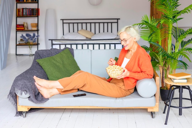 Photo belle femme âgée dans un appartement confortable travaille sur un ordinateur portable belle femme aux cheveux gris travaille en ligne ou regarde des films étudie et communique le concept de vieillesse active