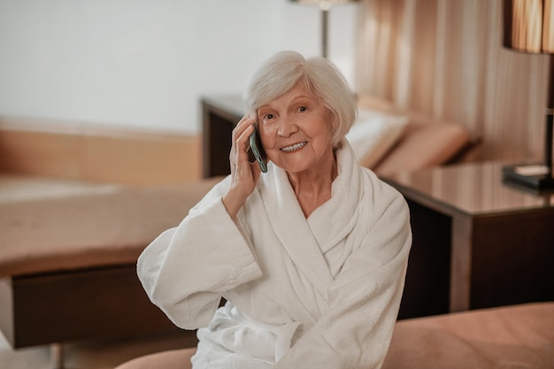 Belle femme âgée en robe blanche avec un téléphone dans les mains