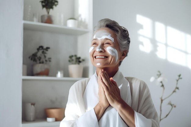 Une belle femme âgée s'applique une crème ou un masque sur le visage.