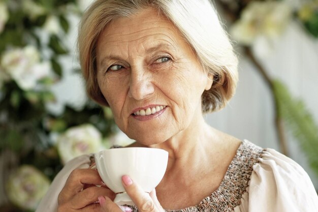 Belle femme âgée souriante buvant du thé