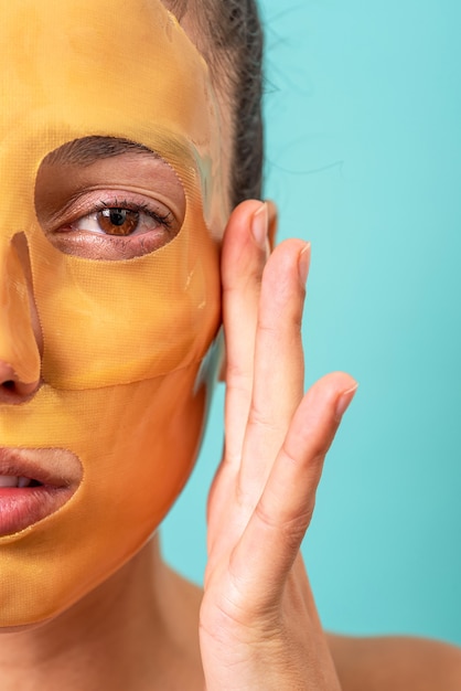 Belle femme à l'aide de traitement de masque de soin de la peau de gel de collagène facial