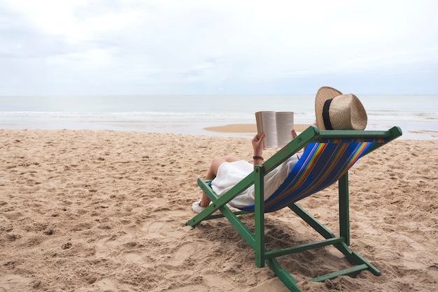 Une belle femme allongée et lisant un livre sur la chaise de plage avec une sensation de détente