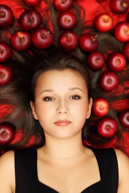 Belle femme allongée sur un tissu rouge avec des pommes