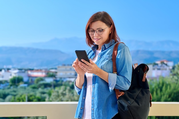 Belle femme des années 40 avec sac à dos smartphone en plein air