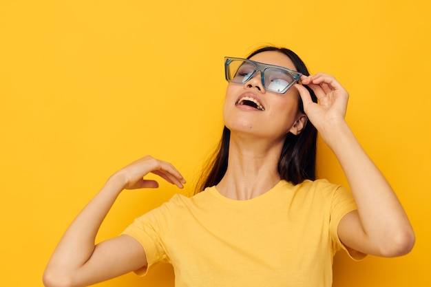 Belle femme d'apparence asiatique à la mode des lunettes de t-shirt jaune