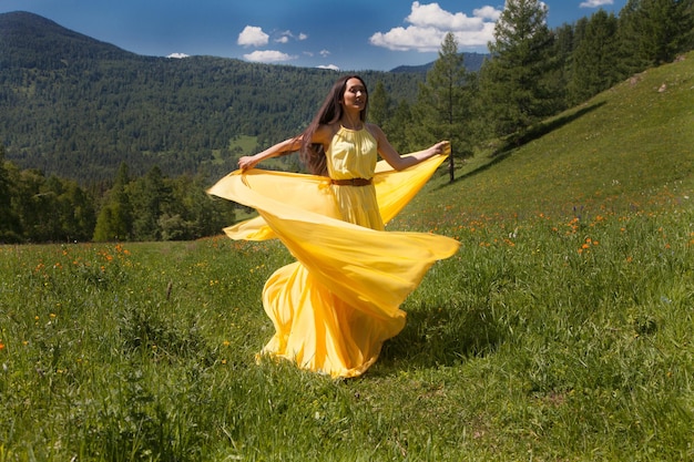 Une belle femme d'apparence asiatique vêtue d'une robe jaune se promène en été dans l'Altaï.