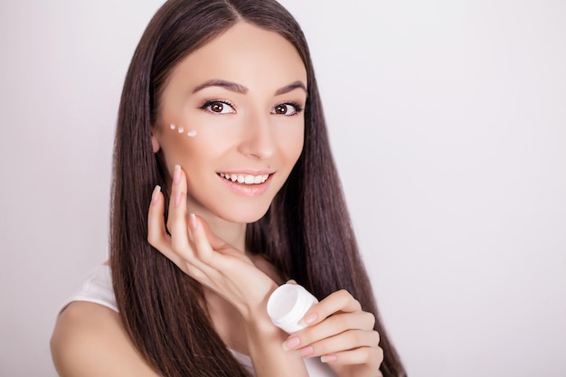 Belle femme appliquant une crème cosmétique pour le visage